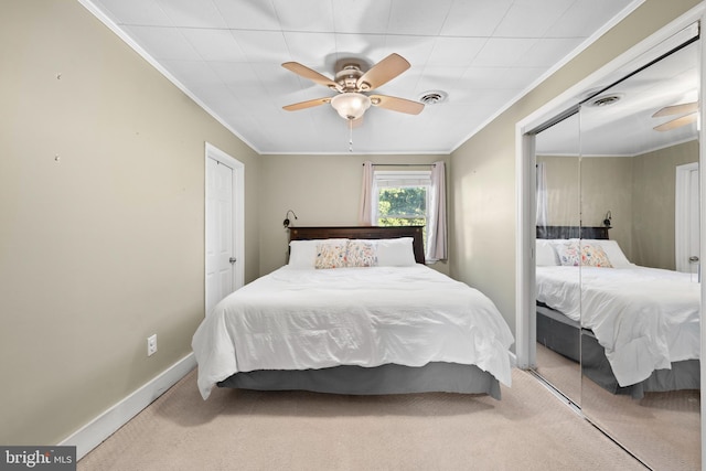 carpeted bedroom featuring a ceiling fan, baseboards, visible vents, a closet, and crown molding