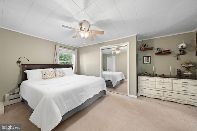 carpeted bedroom featuring a baseboard heating unit, crown molding, a ceiling fan, and a closet