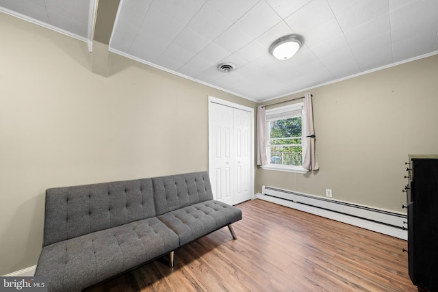 sitting room featuring baseboard heating, ornamental molding, visible vents, and wood finished floors