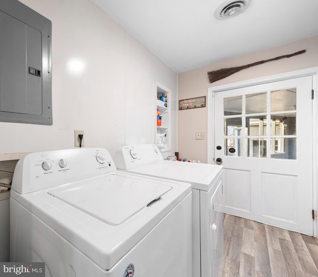 washroom with visible vents, washer and clothes dryer, electric panel, laundry area, and light wood-style floors