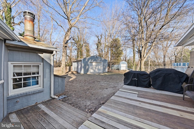 wooden deck featuring grilling area, a storage unit, an outdoor structure, and fence