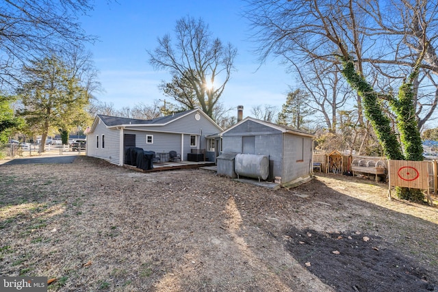 back of property featuring a deck, heating fuel, and fence