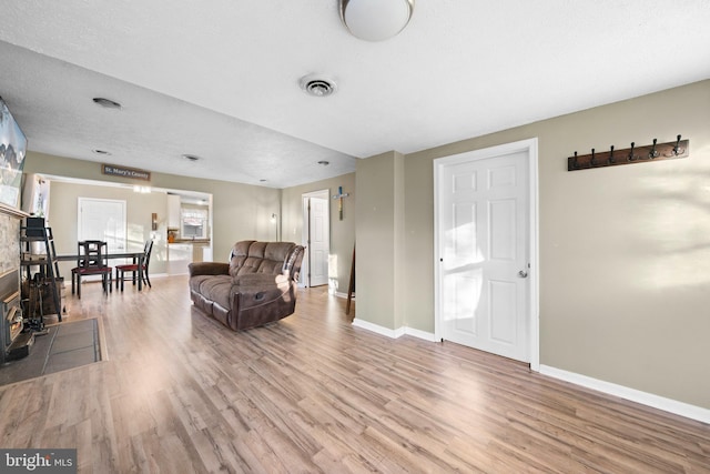 living room featuring visible vents, a textured ceiling, baseboards, and wood finished floors