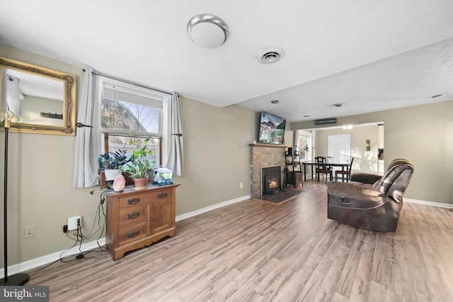 sitting room featuring visible vents, baseboards, light wood-style floors, and a fireplace with flush hearth