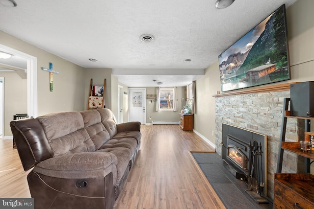 living room featuring wood finished floors, baseboards, visible vents, a fireplace, and a textured ceiling