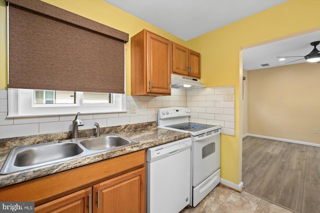 kitchen with under cabinet range hood, white appliances, a sink, brown cabinets, and tasteful backsplash