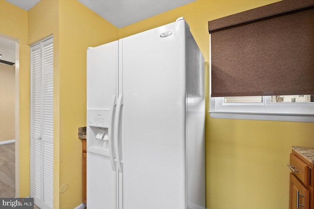 kitchen with white fridge with ice dispenser and stone counters