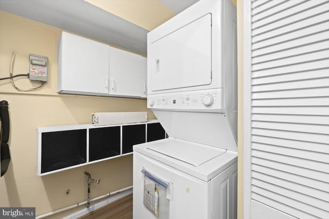 clothes washing area with stacked washer / dryer, dark wood-style flooring, and cabinet space