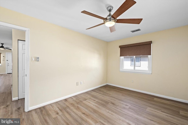 empty room with visible vents, ceiling fan, baseboards, and wood finished floors