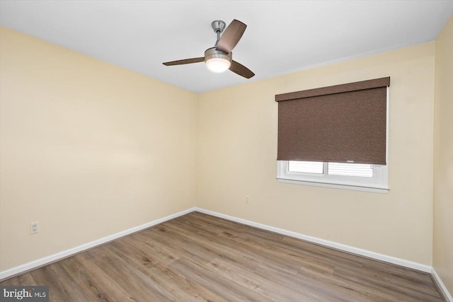 spare room featuring a ceiling fan, baseboards, and wood finished floors