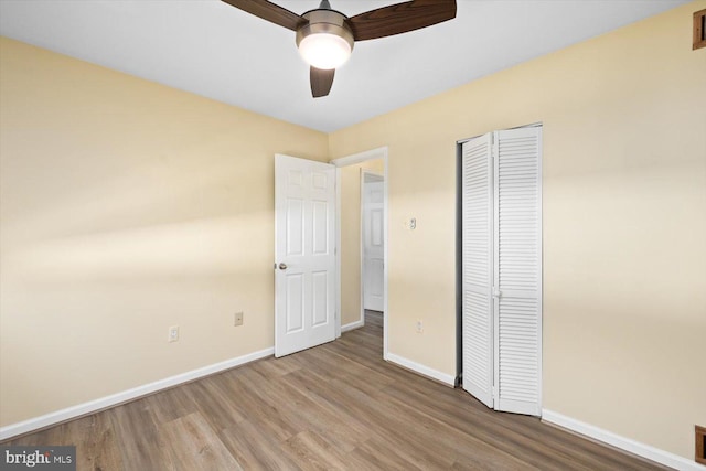 unfurnished bedroom featuring a closet, wood finished floors, and baseboards