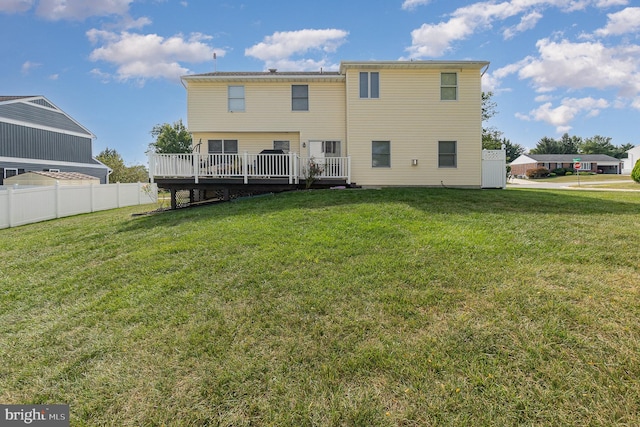 rear view of property with fence, a wooden deck, and a lawn