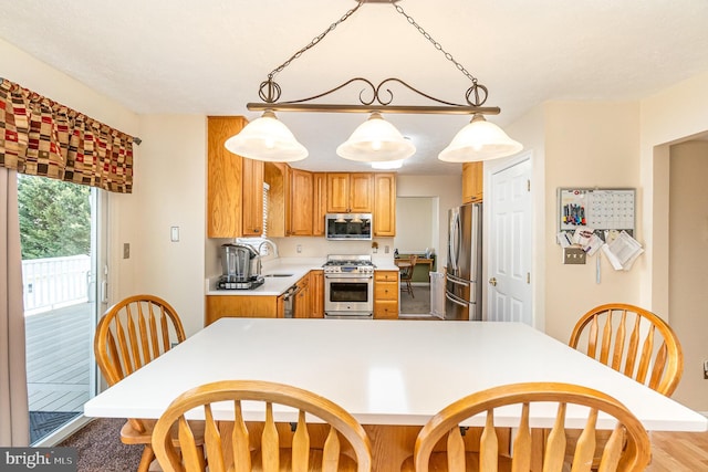 kitchen with light countertops, appliances with stainless steel finishes, a sink, and pendant lighting