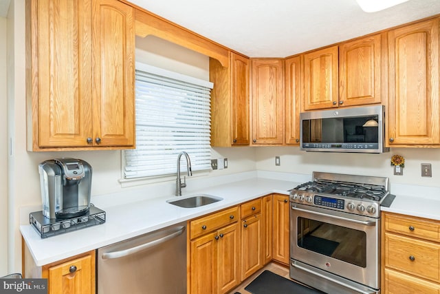 kitchen featuring appliances with stainless steel finishes, light countertops, and a sink