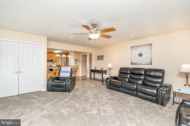 carpeted living area with a textured ceiling and ceiling fan