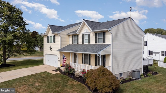 traditional home featuring central AC unit, covered porch, a garage, driveway, and a front yard