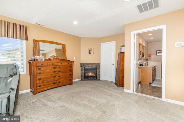 bedroom with carpet floors, a high end fireplace, visible vents, and baseboards