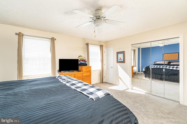 bedroom with a closet, a ceiling fan, light carpet, a textured ceiling, and baseboards