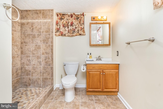 full bath featuring toilet, baseboards, tiled shower, and vanity