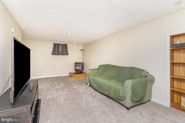 living room with carpet floors, a wood stove, a textured ceiling, and baseboards