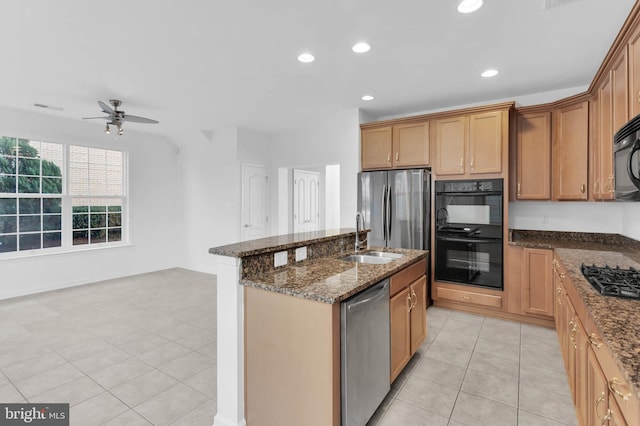 kitchen featuring light tile patterned floors, recessed lighting, a kitchen island with sink, dark stone counters, and black appliances