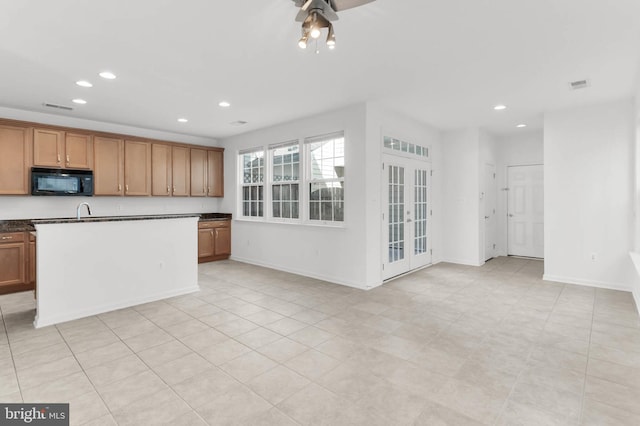 kitchen with black microwave, recessed lighting, visible vents, brown cabinetry, and dark countertops