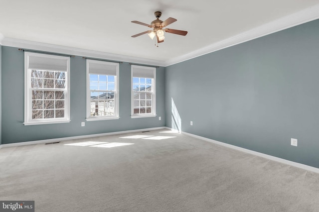 carpeted spare room featuring a ceiling fan, visible vents, crown molding, and baseboards