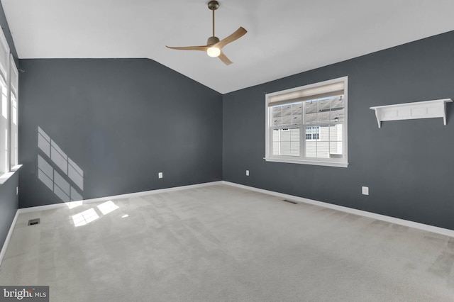 carpeted spare room featuring visible vents, vaulted ceiling, baseboards, and ceiling fan