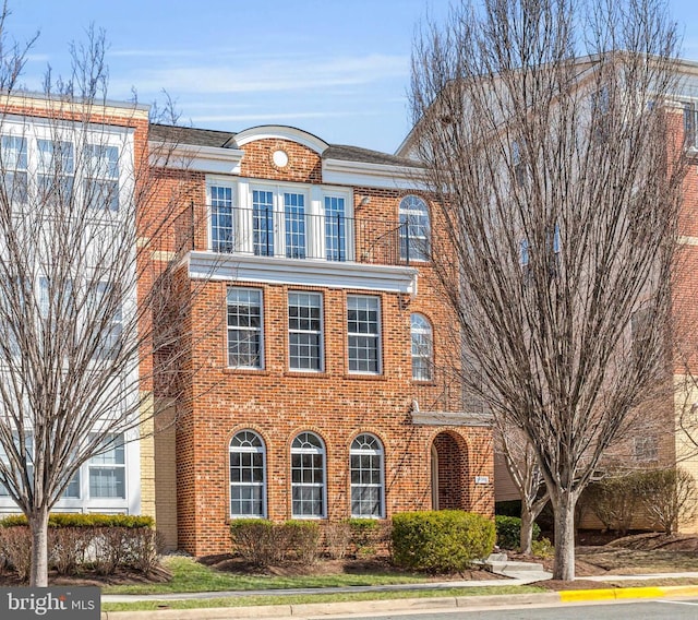 view of front facade with a balcony and brick siding