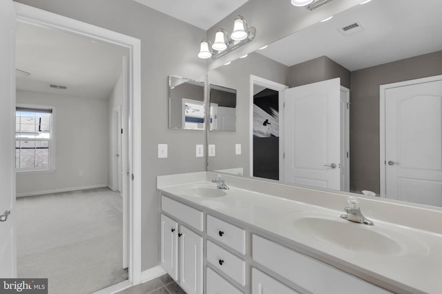 bathroom with double vanity, a sink, visible vents, and baseboards