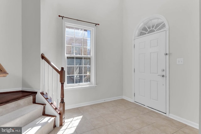 entrance foyer featuring light tile patterned flooring, stairway, and baseboards