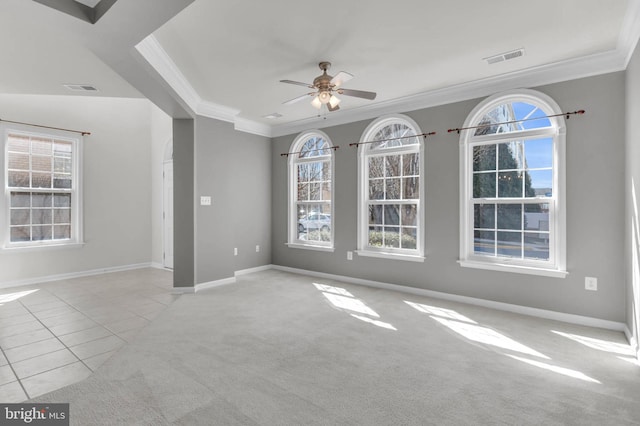 tiled spare room with a wealth of natural light, carpet, visible vents, and crown molding