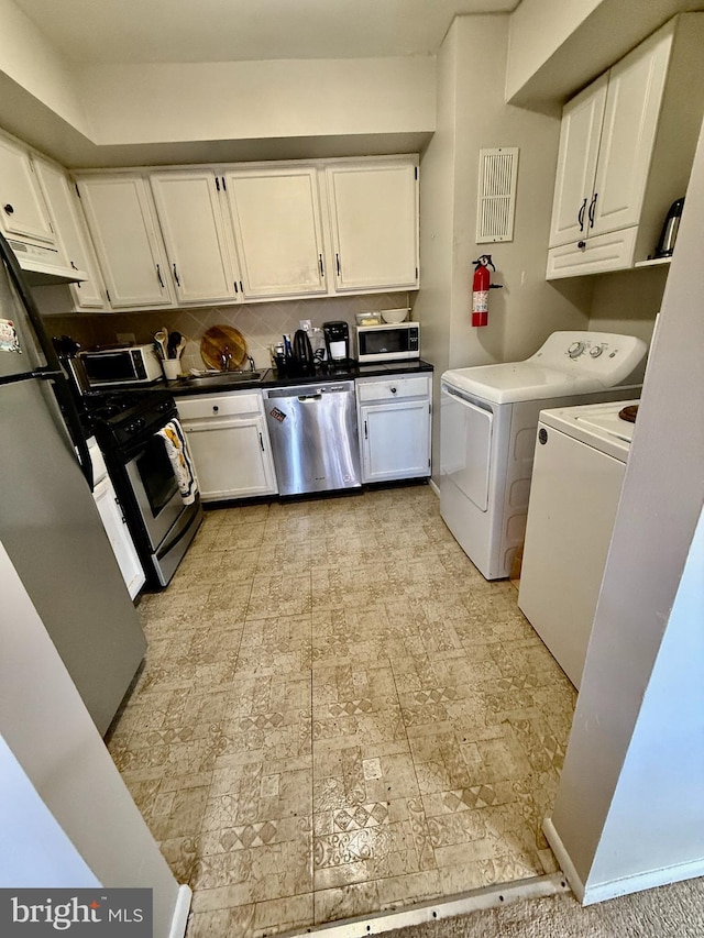 kitchen featuring appliances with stainless steel finishes, washing machine and clothes dryer, and white cabinets