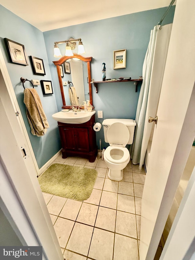 bathroom featuring baseboards, a shower with shower curtain, toilet, tile patterned flooring, and vanity