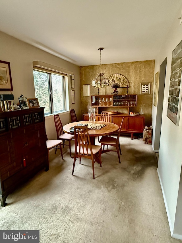 dining space with a chandelier, carpet flooring, and baseboards