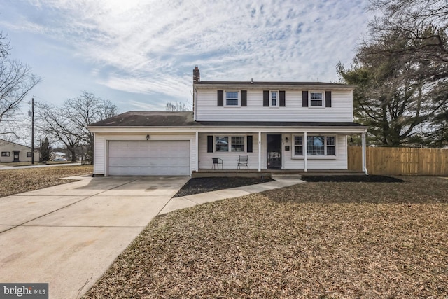 traditional home with a garage, concrete driveway, a chimney, covered porch, and fence