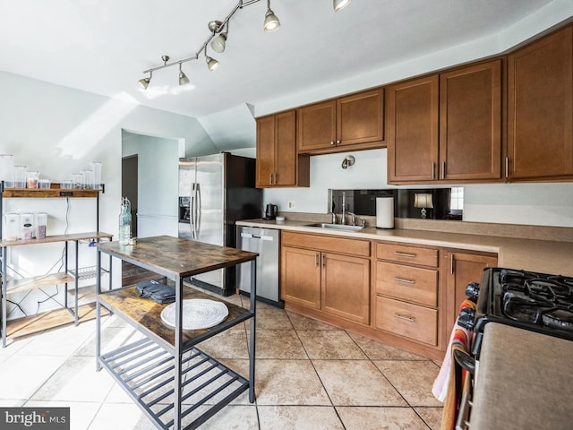 kitchen with light tile patterned flooring, a sink, light countertops, stainless steel dishwasher, and range with gas cooktop