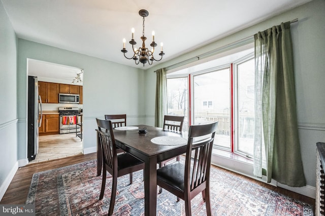 dining area with baseboards, light wood-style flooring, and a notable chandelier