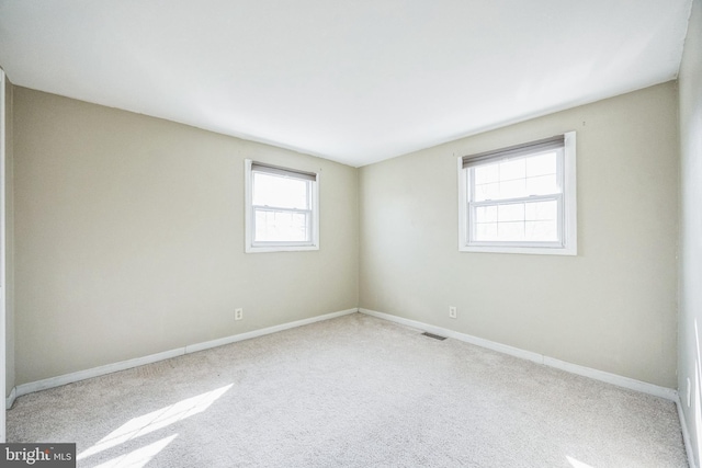 carpeted spare room with baseboards and visible vents