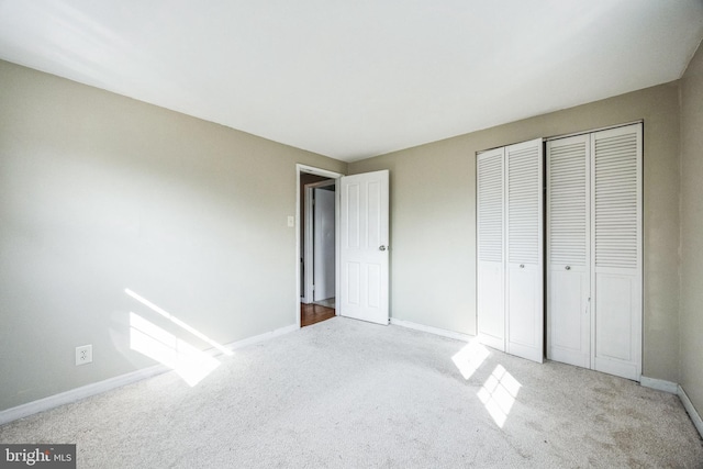 unfurnished bedroom featuring carpet, a closet, and baseboards