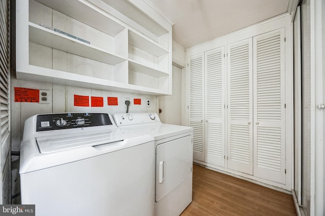 clothes washing area featuring wood finished floors, laundry area, and separate washer and dryer