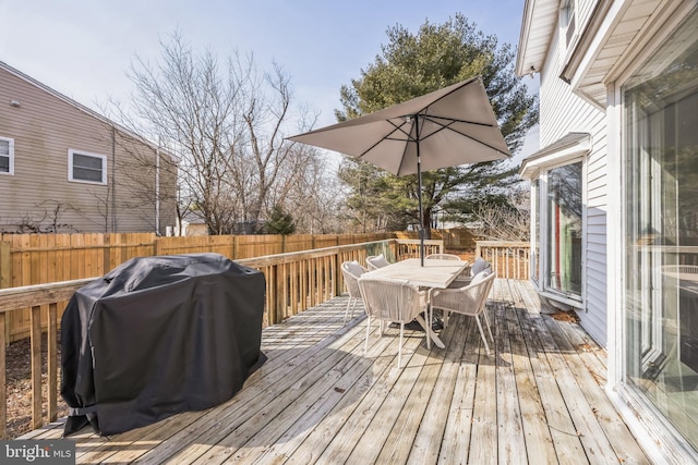 wooden deck featuring a grill, fence, and outdoor dining space