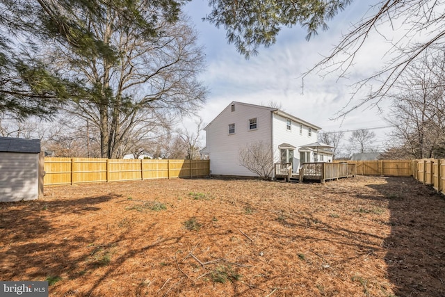 view of yard with a fenced backyard, a storage unit, an outbuilding, and a wooden deck