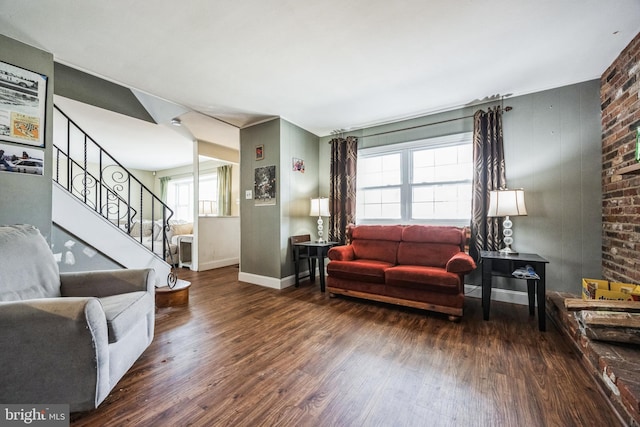 living area featuring baseboards, stairway, and wood finished floors