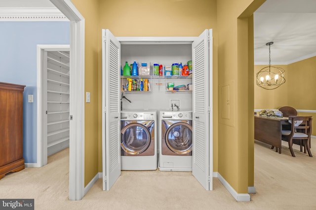 clothes washing area featuring a chandelier, laundry area, washer and dryer, and carpet