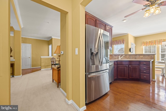 kitchen featuring a peninsula, ornamental molding, decorative backsplash, dark brown cabinets, and appliances with stainless steel finishes