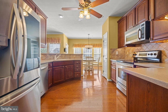 kitchen featuring stainless steel appliances, light wood-style floors, a healthy amount of sunlight, and light countertops