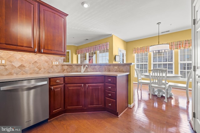 kitchen featuring decorative backsplash, a peninsula, stainless steel dishwasher, wood-type flooring, and a sink