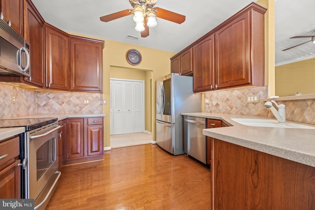 kitchen with a sink, stainless steel appliances, ceiling fan, and light countertops