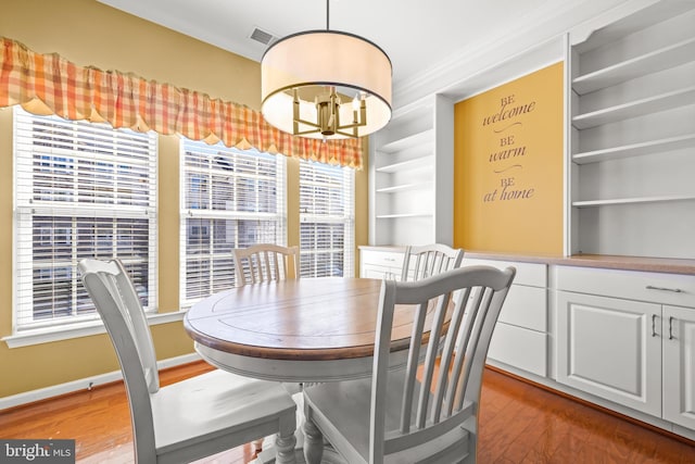 dining room featuring visible vents, a notable chandelier, light wood-style flooring, ornamental molding, and baseboards